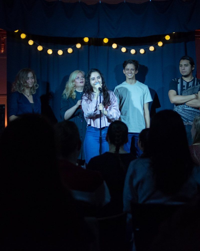 Naira at the microphone with other comedians on stage